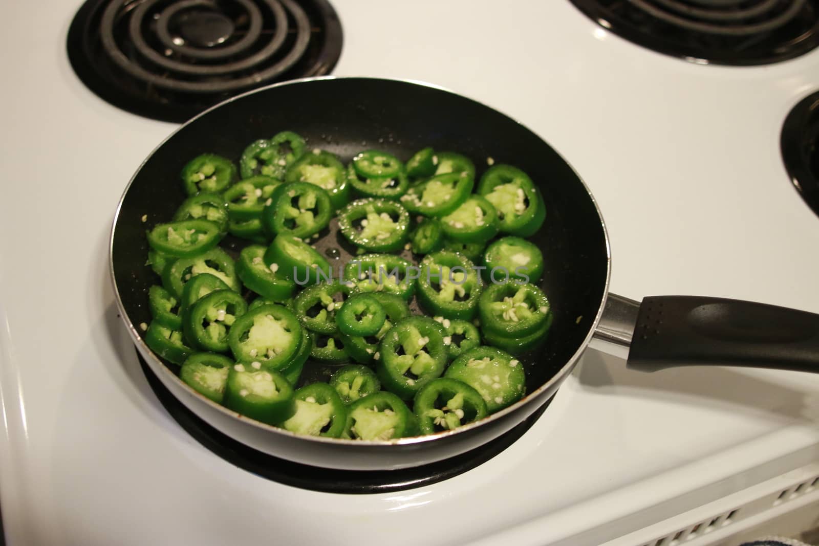 cooking jalapenos in a frying pan to make them for sandwiches.