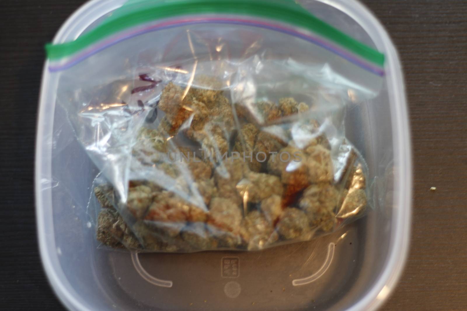 Looking down at a zipper bag full of marijuana on its side spilling buds out the open top isolated with a white background.