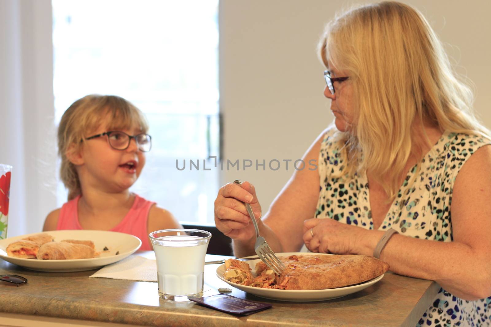 Grandma and granddaughter eating dinner together at a kitchen table by mynewturtle1