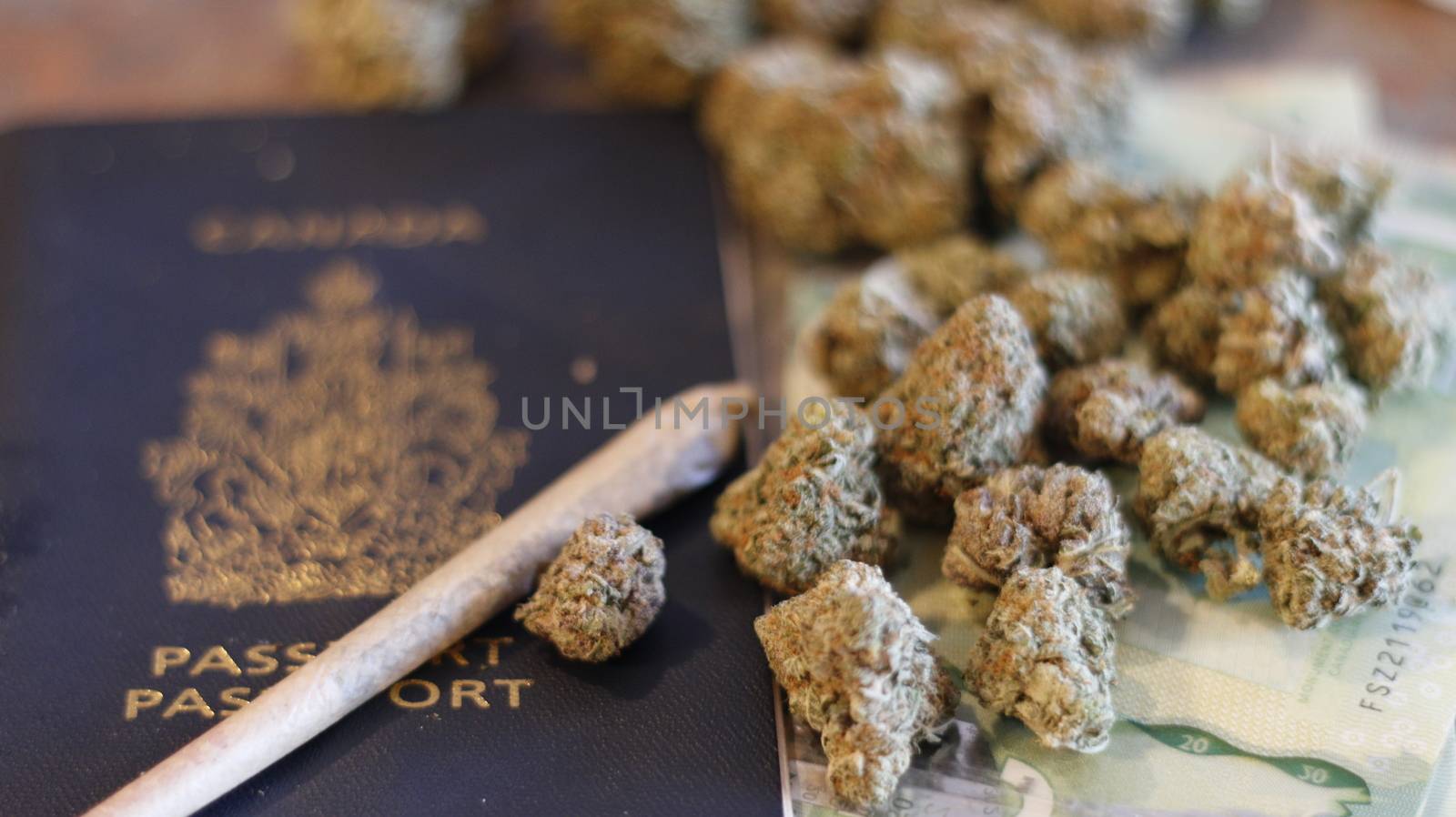 Canadian passport with marijuana, money, and joint near it. theme of marijuana legalization by mynewturtle1