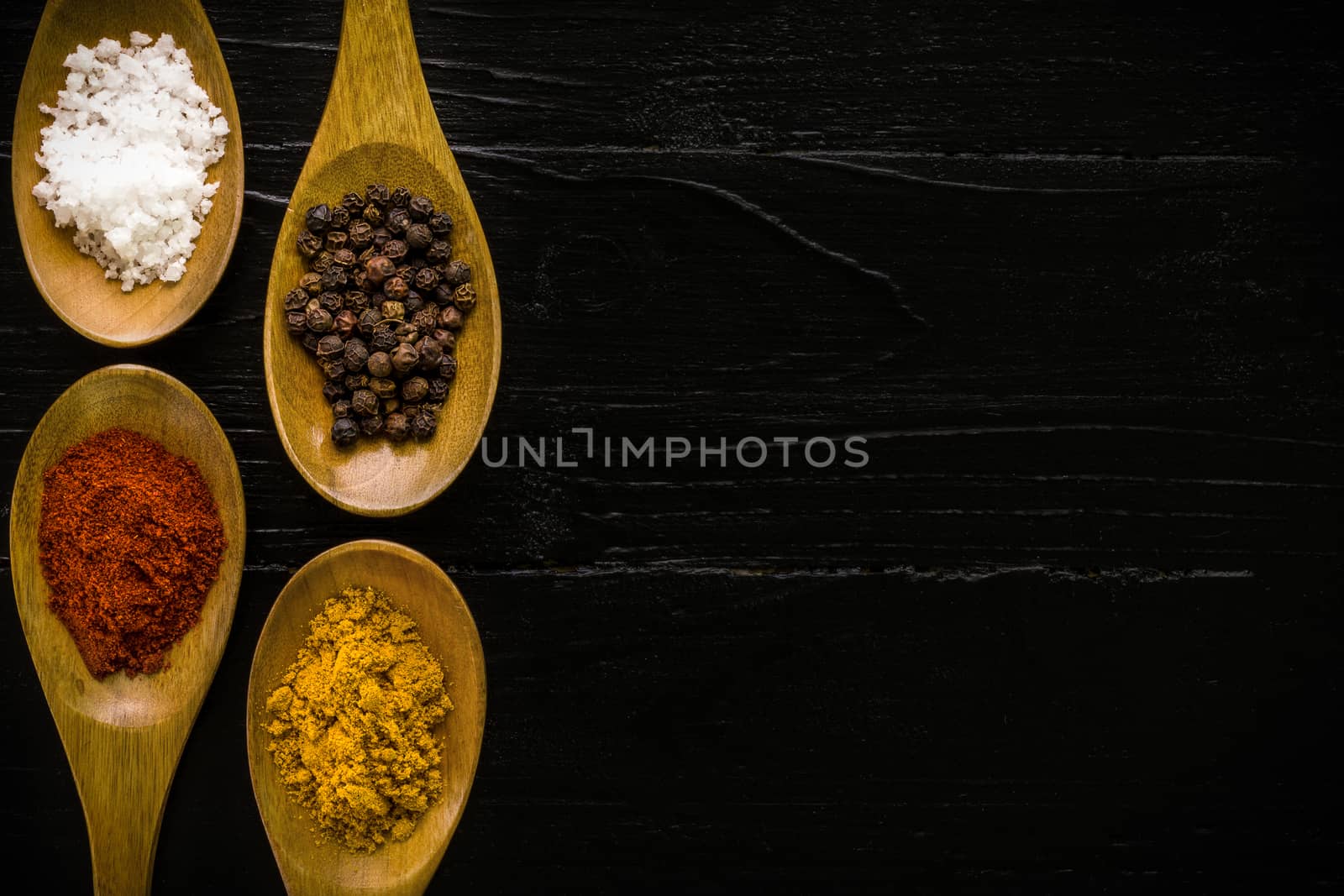 Various kinds of spice in wooden spoon background.