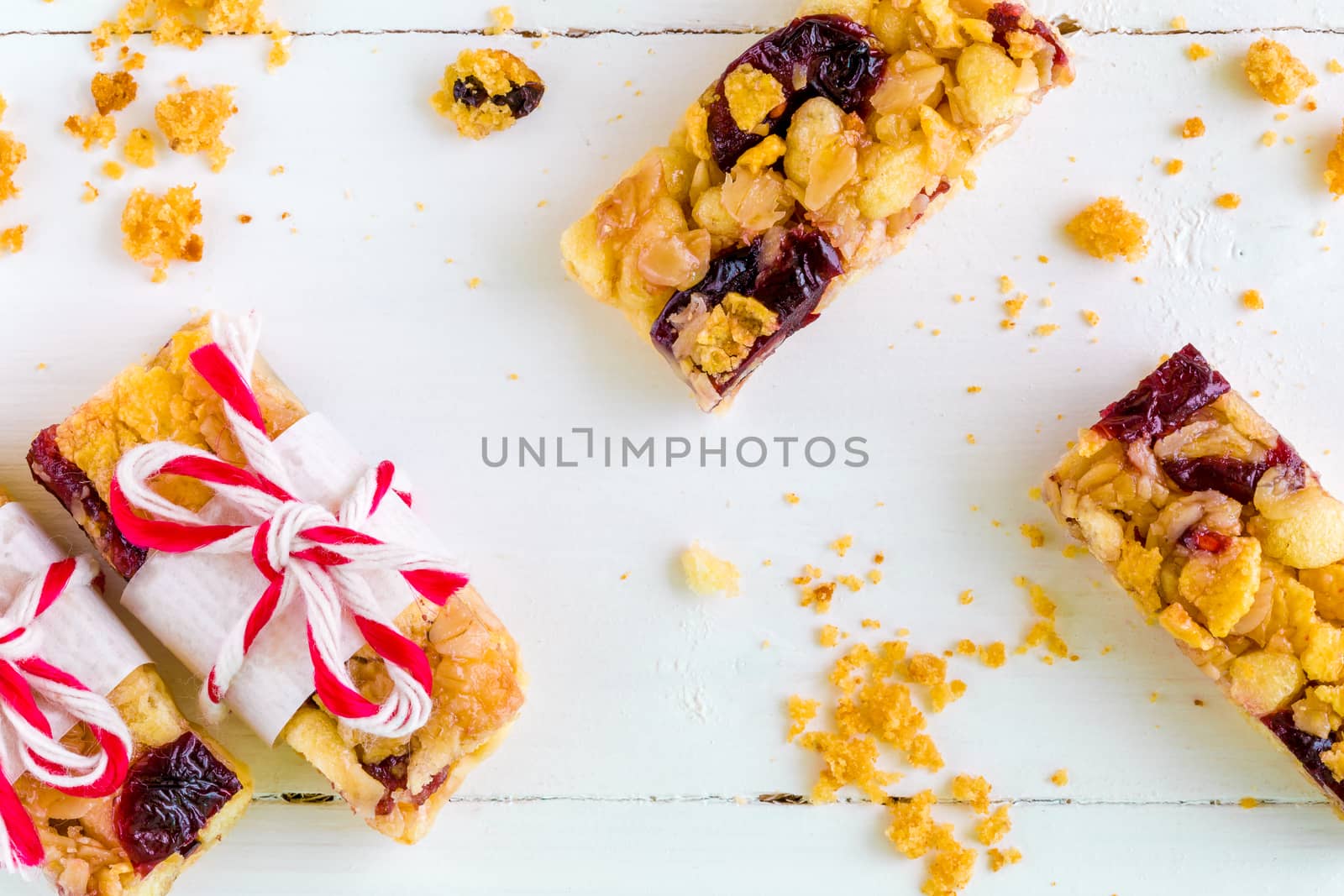 Muesli or granola bars with cranberry on white wooden background.