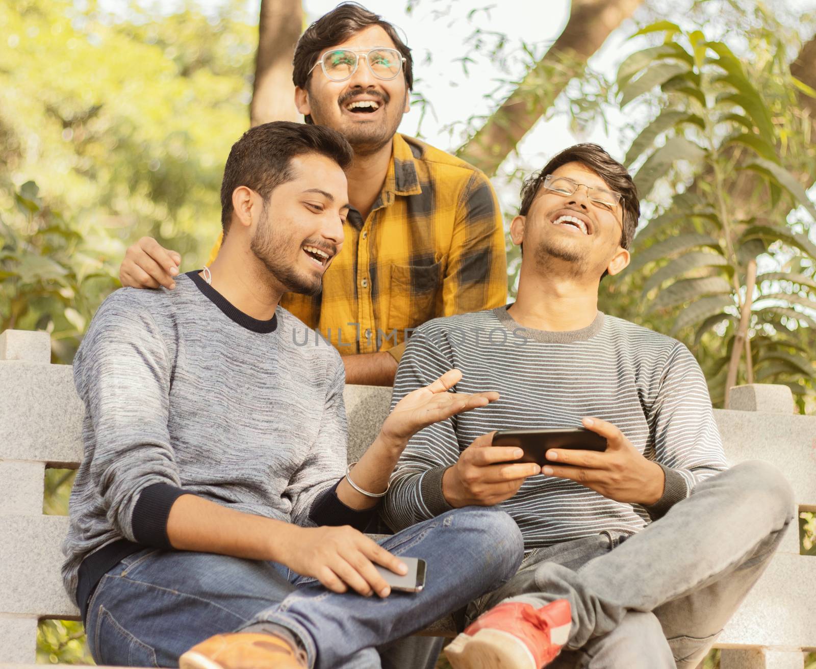 Group of friends laughing loud by watching into smartphone - Concept of young millennial people using technology, Social Media, Internet and mobile addiction - Filter Image. by lakshmiprasad.maski@gmai.com