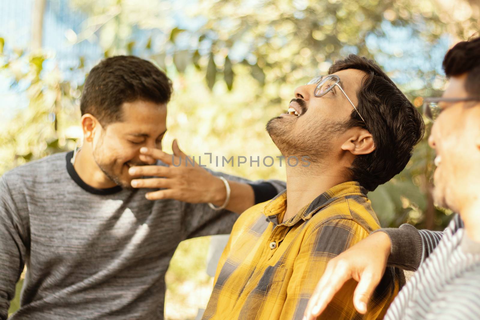 Three young adult laughing and having fun at picnic - Concept of happy friendship - youthful Male friends socializing at college