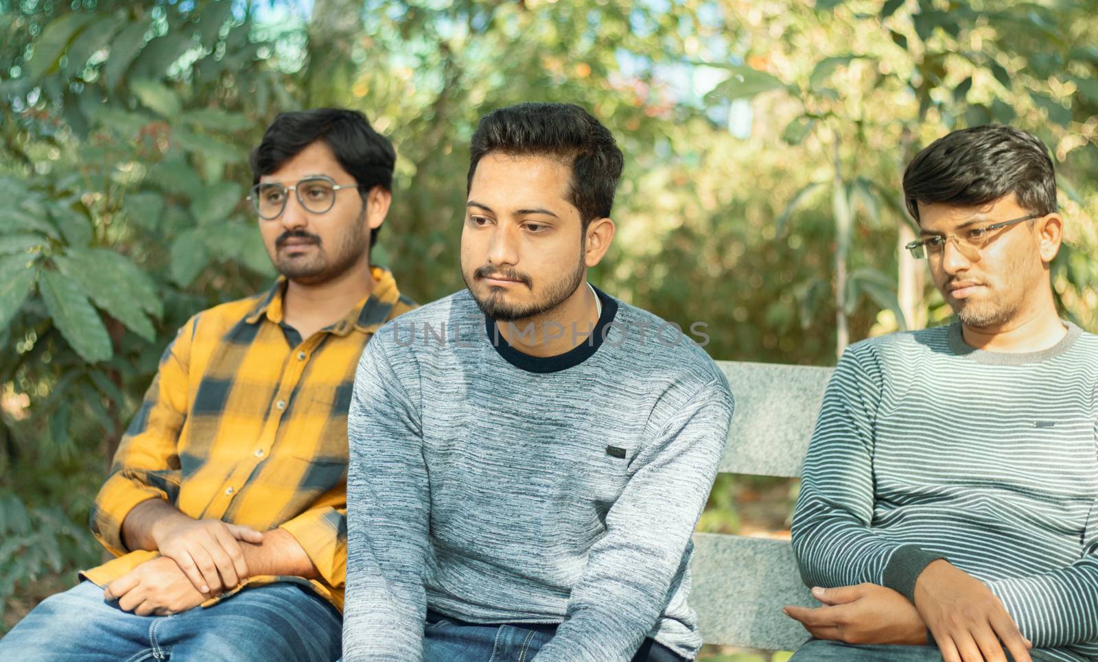 Three bored looking friends on table at park - Concept of boredom, lack of communication and fight between friends.