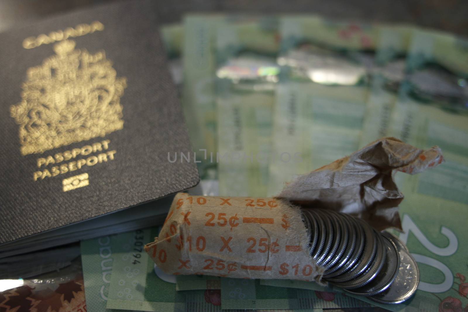 Canadian passport on twenty dollar bills and next to canadian coins. Theme of travel or immigration by mynewturtle1