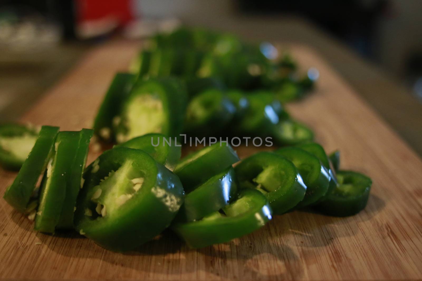 Sliced fresh green and red jalapenos on a black stone board. Next to hot pepper lies a knife. Top view. Preparation for. Fermentation, cooking. Copy space by mynewturtle1