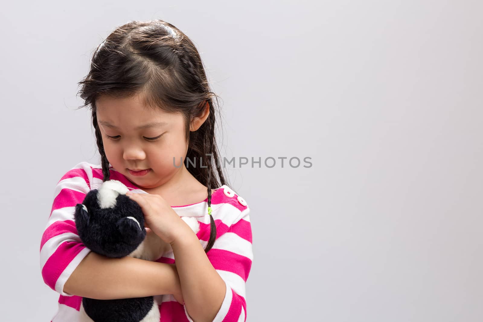 Young girl holding kitten doll in her arms.
