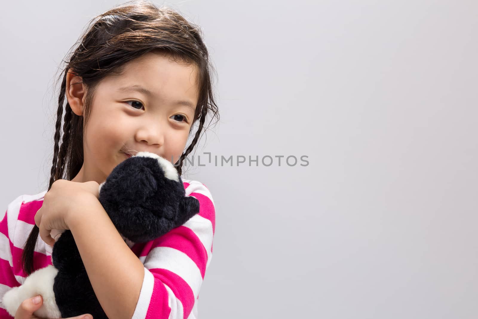 Young girl holding kitten doll in her arms.
