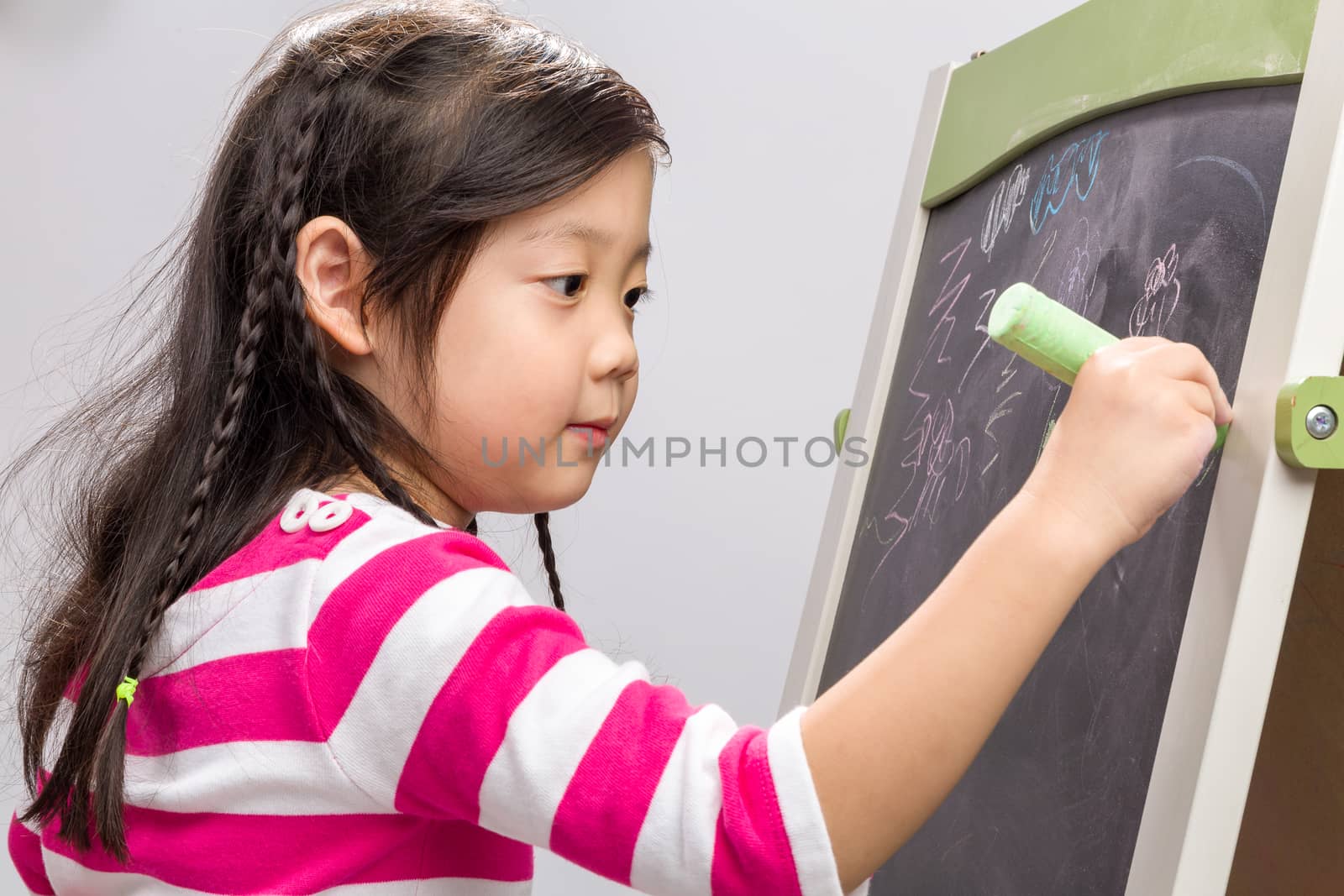 Young girl writing on blackboard on white background.