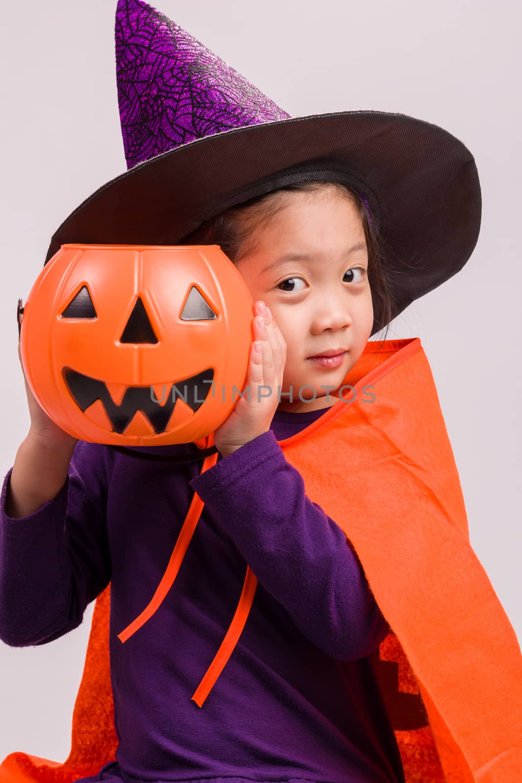 Child in Halloween costume with big pumpkin.