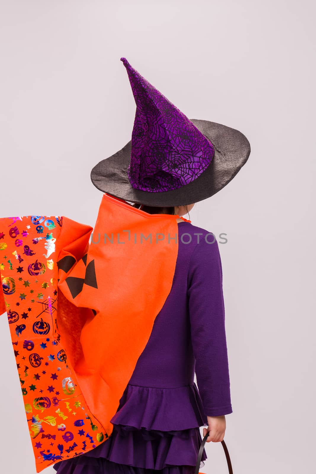 Child in Halloween costume with big pumpkin.