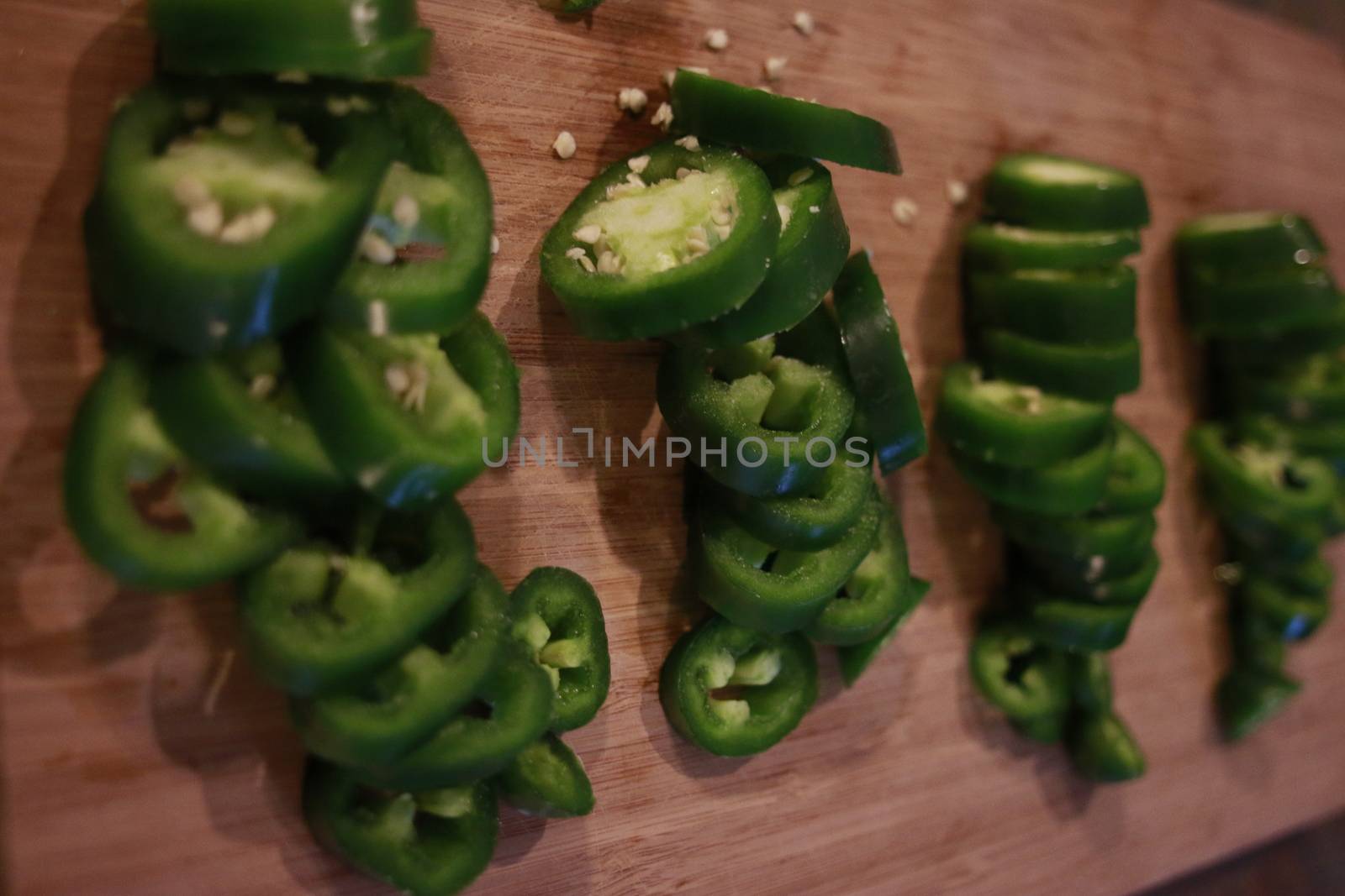 Sliced fresh green and red jalapenos on a black stone board. Next to hot pepper lies a knife. Top view. Preparation for. Fermentation, cooking. Copy space.