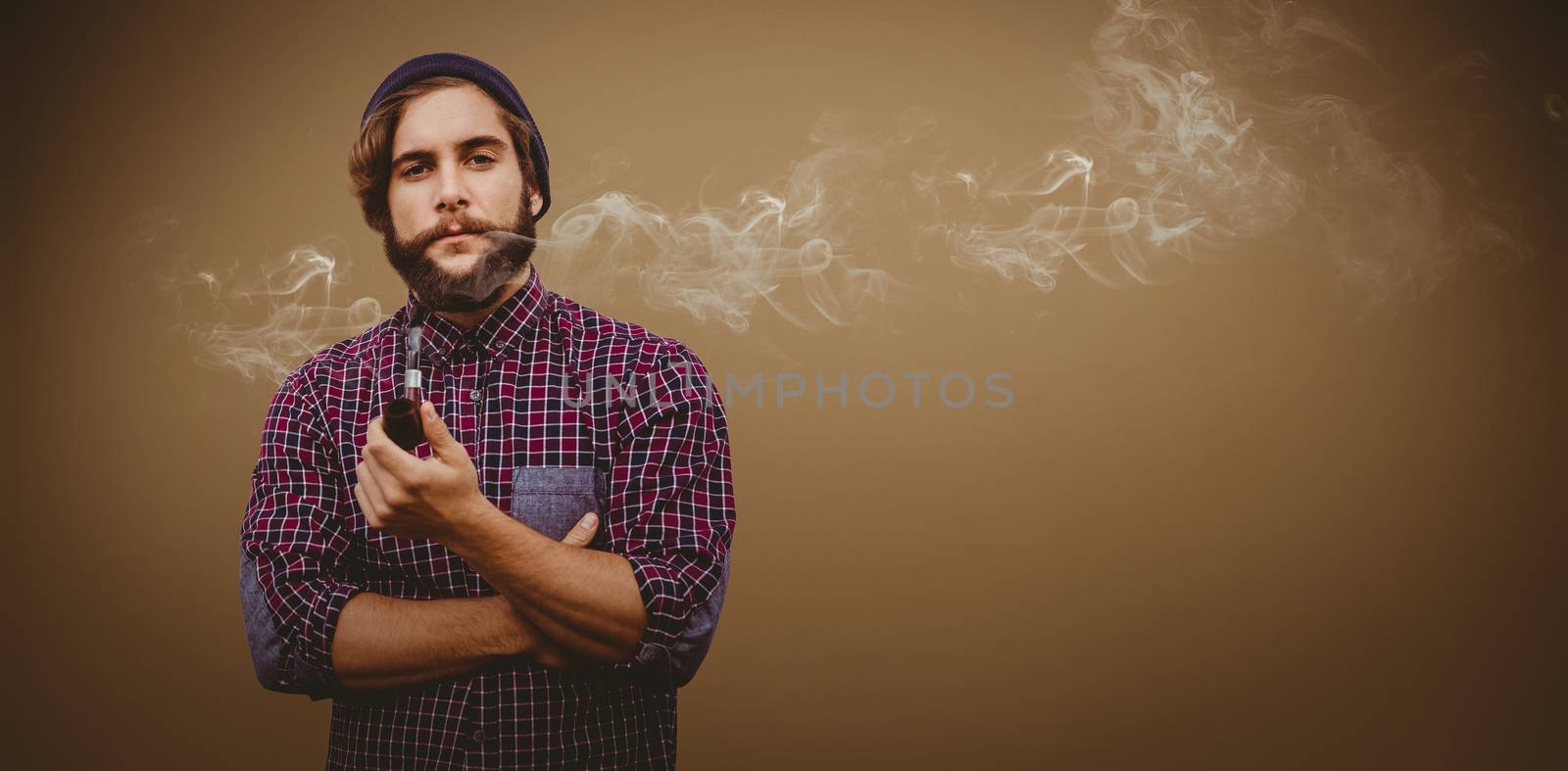 Portrait of confident hipster holding smoking pipe against grey background with vignette