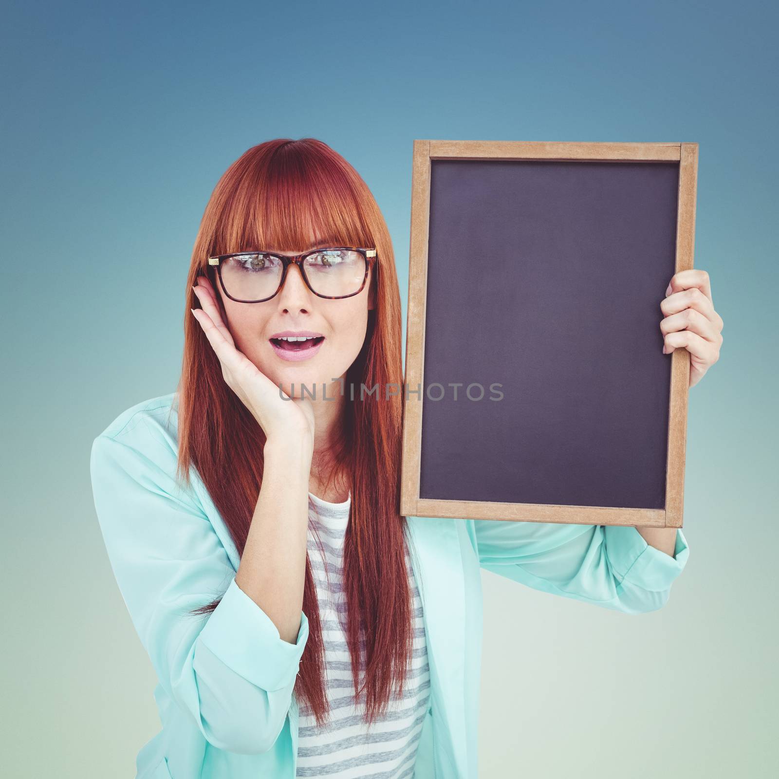 Smiling hipster woman holding blackboard against dark blue green background