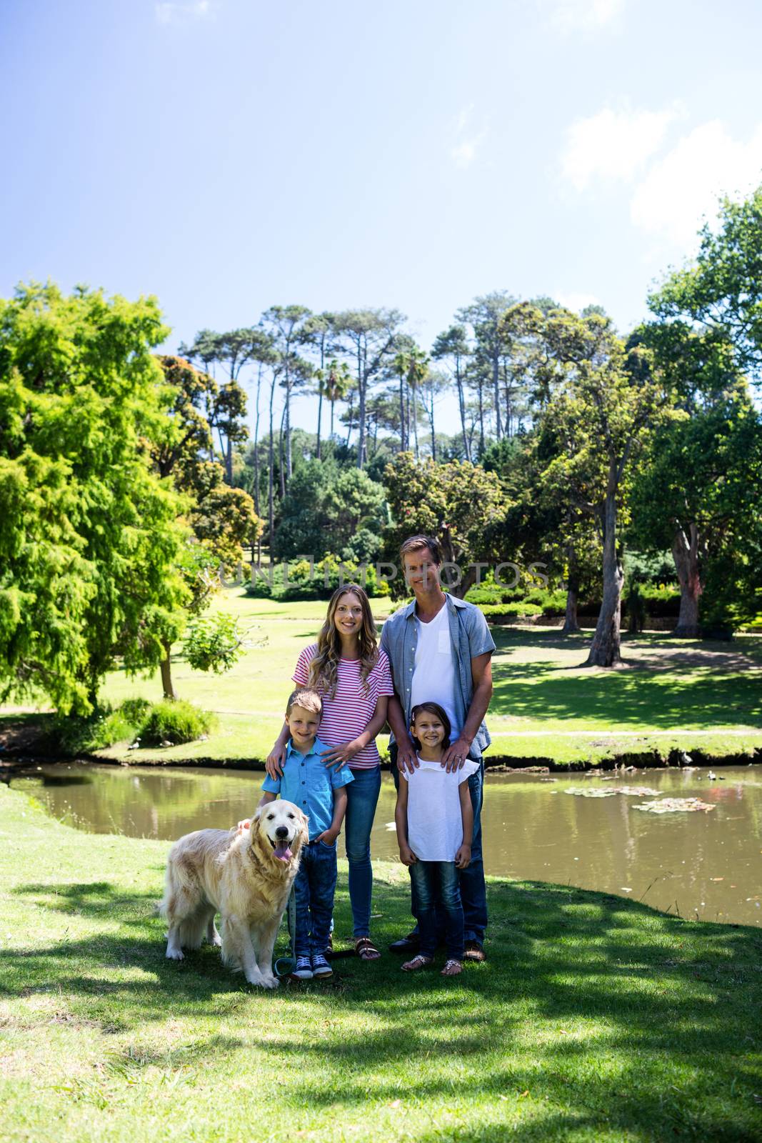 Happy family standing in the park with their dog