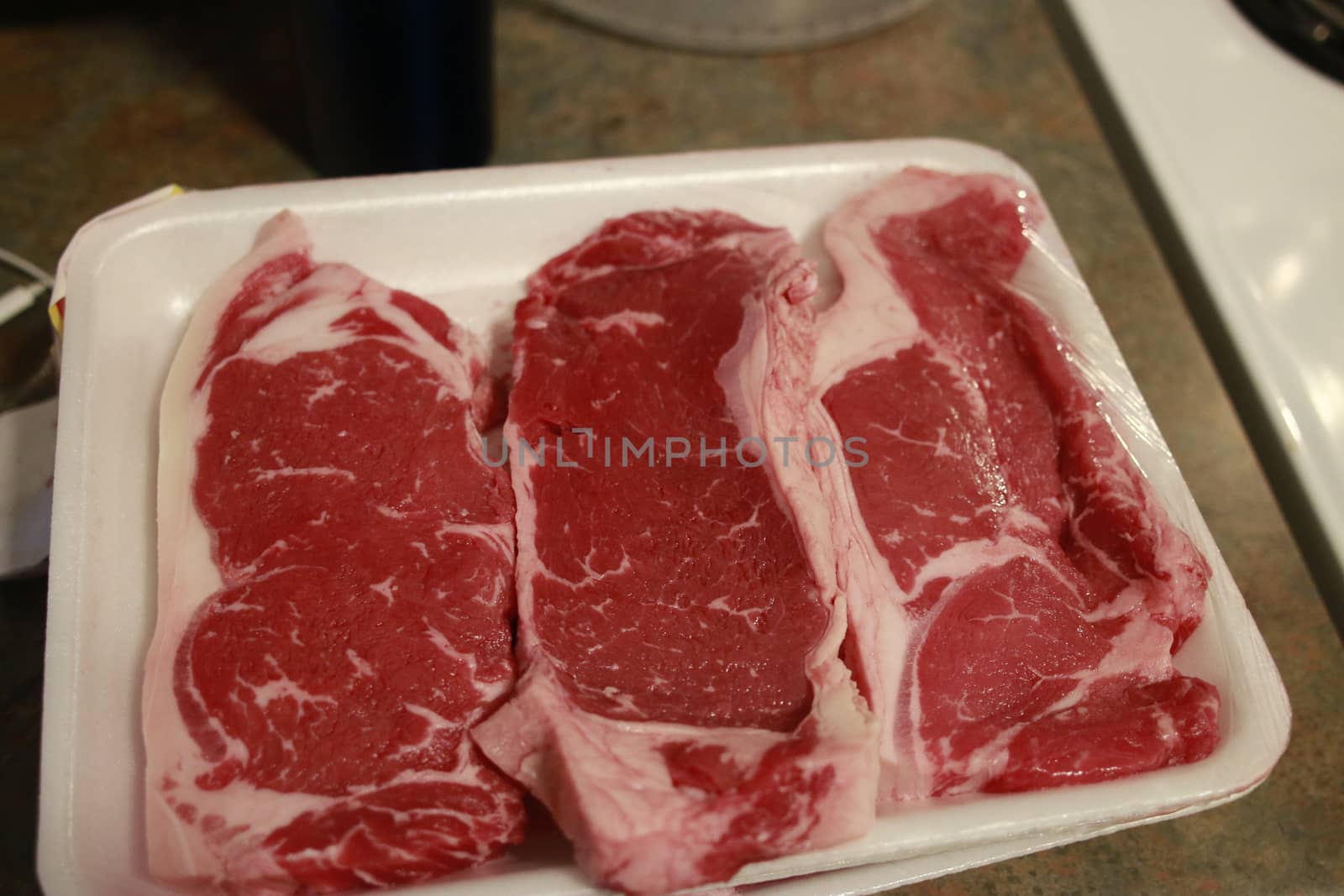 fresh raw striploin steak on wooden Board on wooden background with salt and pepper in a rustic style, top view