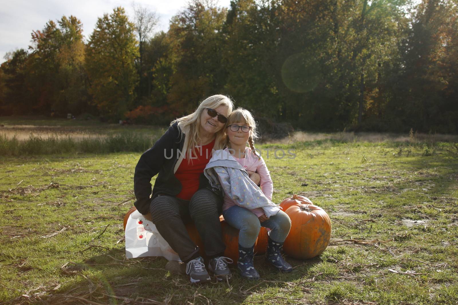 Grandma and granddaughter at a pumpkin patch enjoying the fall activity. Theme of multi-generational family activities..