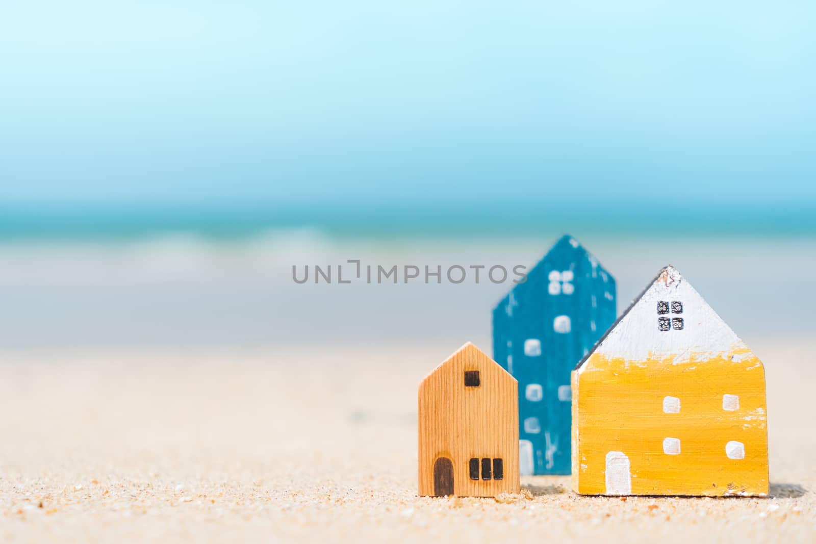 Model of a little house on sand with nature beach background. Dream life concept.