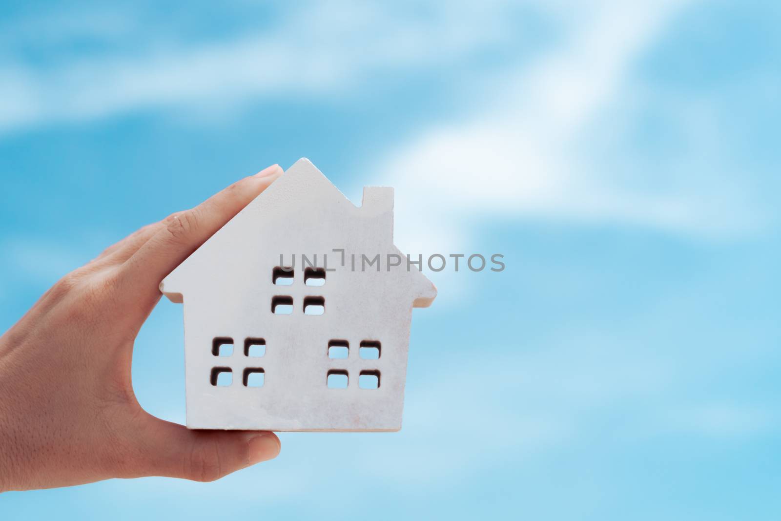 Copyspace with model of a little house that woman holds it background. Dream family life concept.