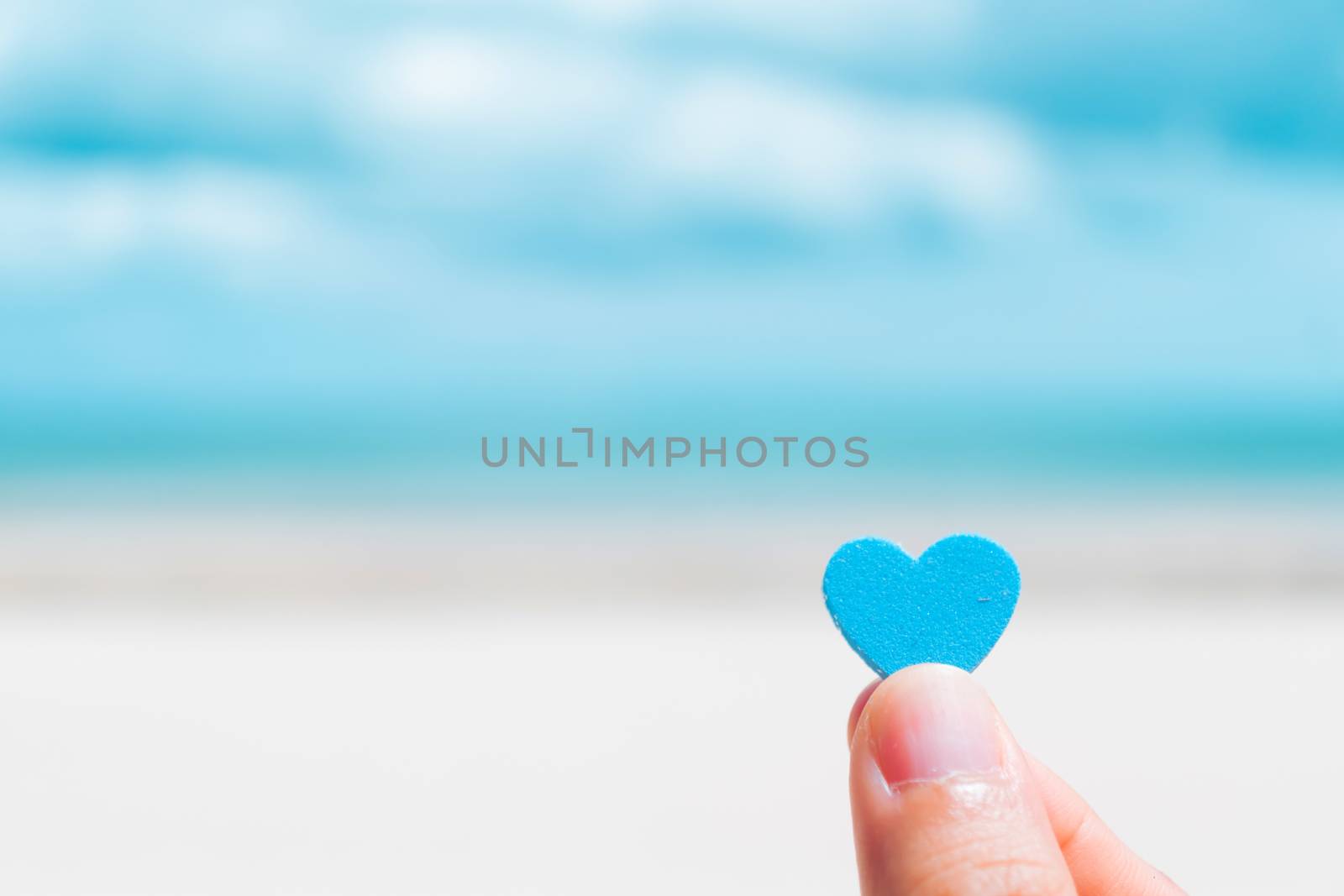 Hand hold little heart meaning feel love with summer beach with blue sky. by Suwant