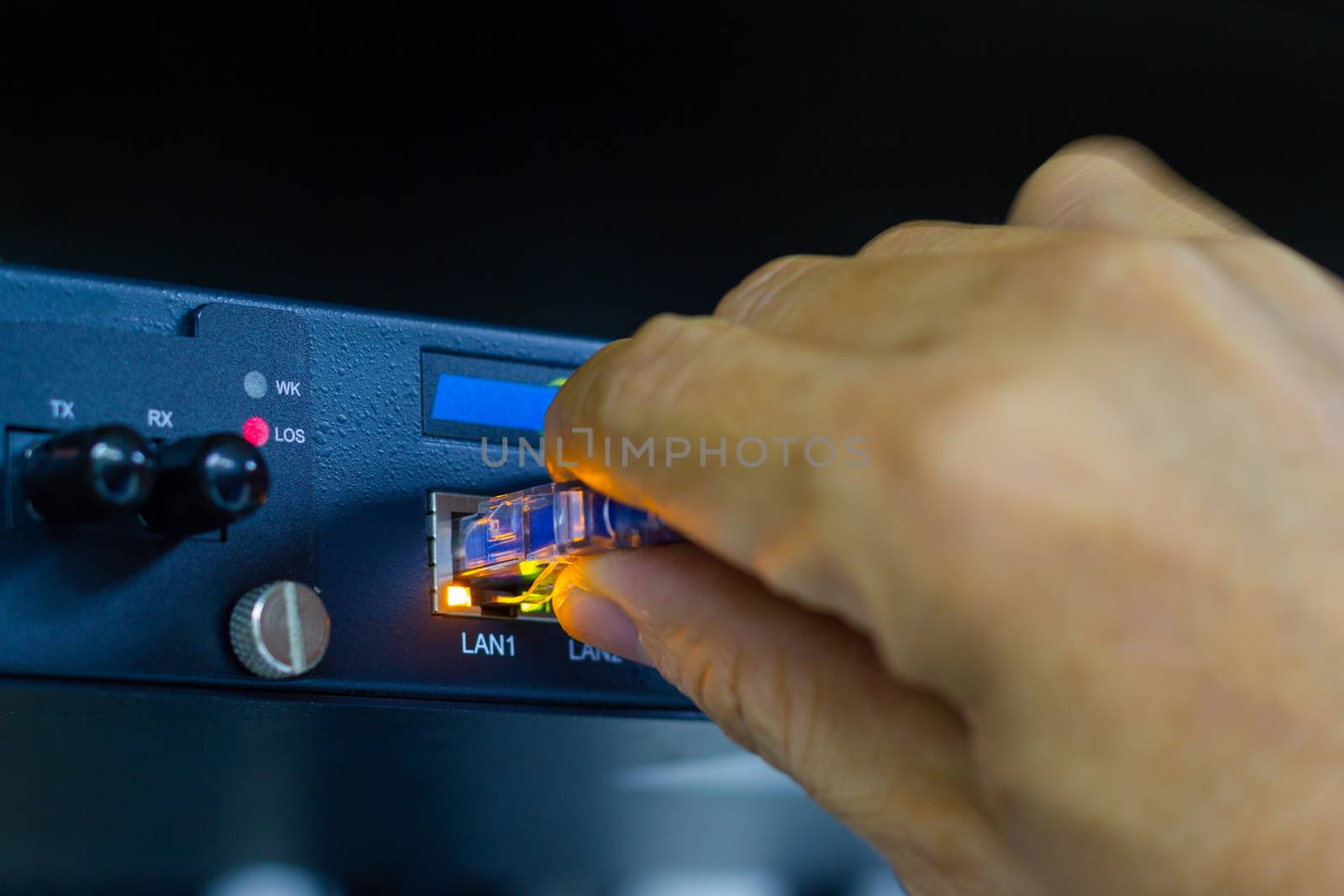 Hand of man holding The network cables to connect SFP module port in the Datacenter room, concept Communication technology