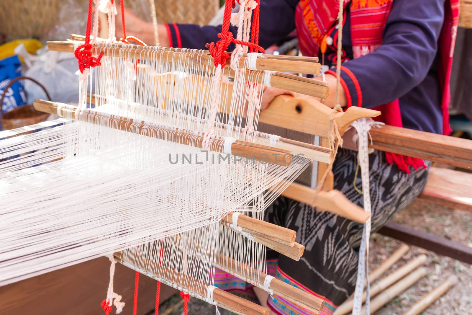 Old women are using the machine - Household Loom weaving - for homemade silk or textile production of Thailand