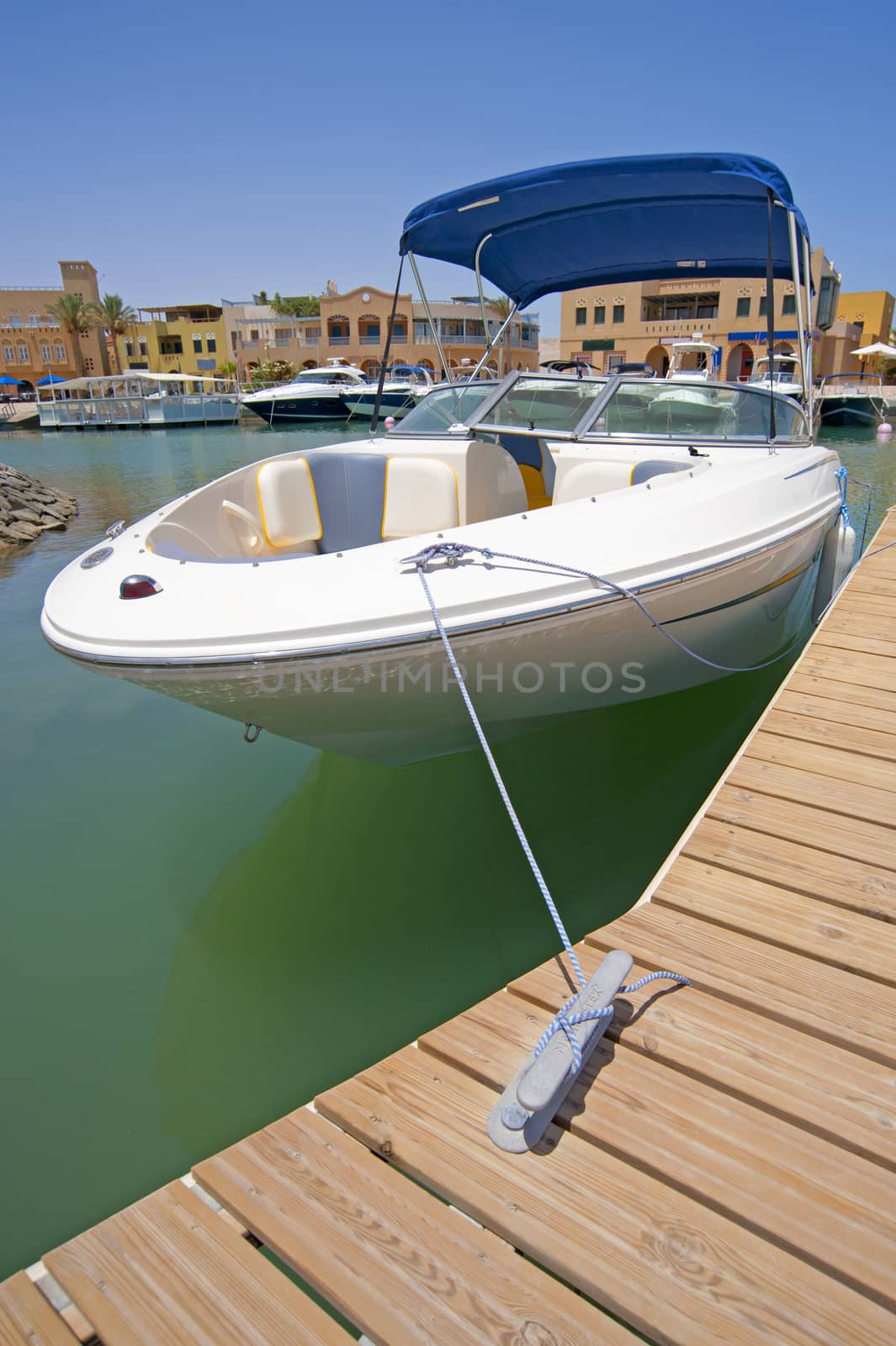 A luxury speedboat moored to a private jetty in a tropical marina
