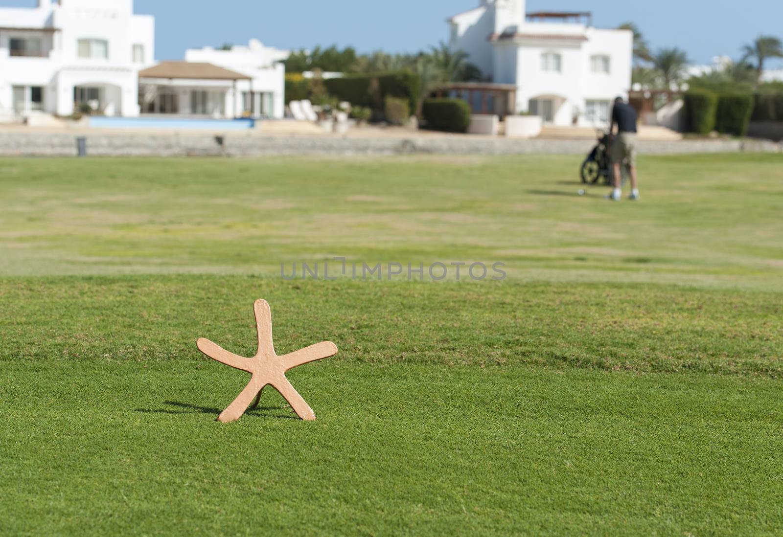 Star shaped tee marker on a golf course with golfer in the distance on fairway
