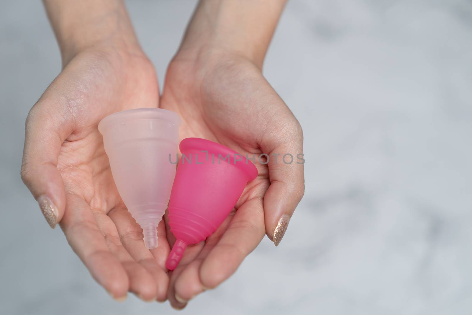Close up of woman hand holding menstrual cup. by sirawit99