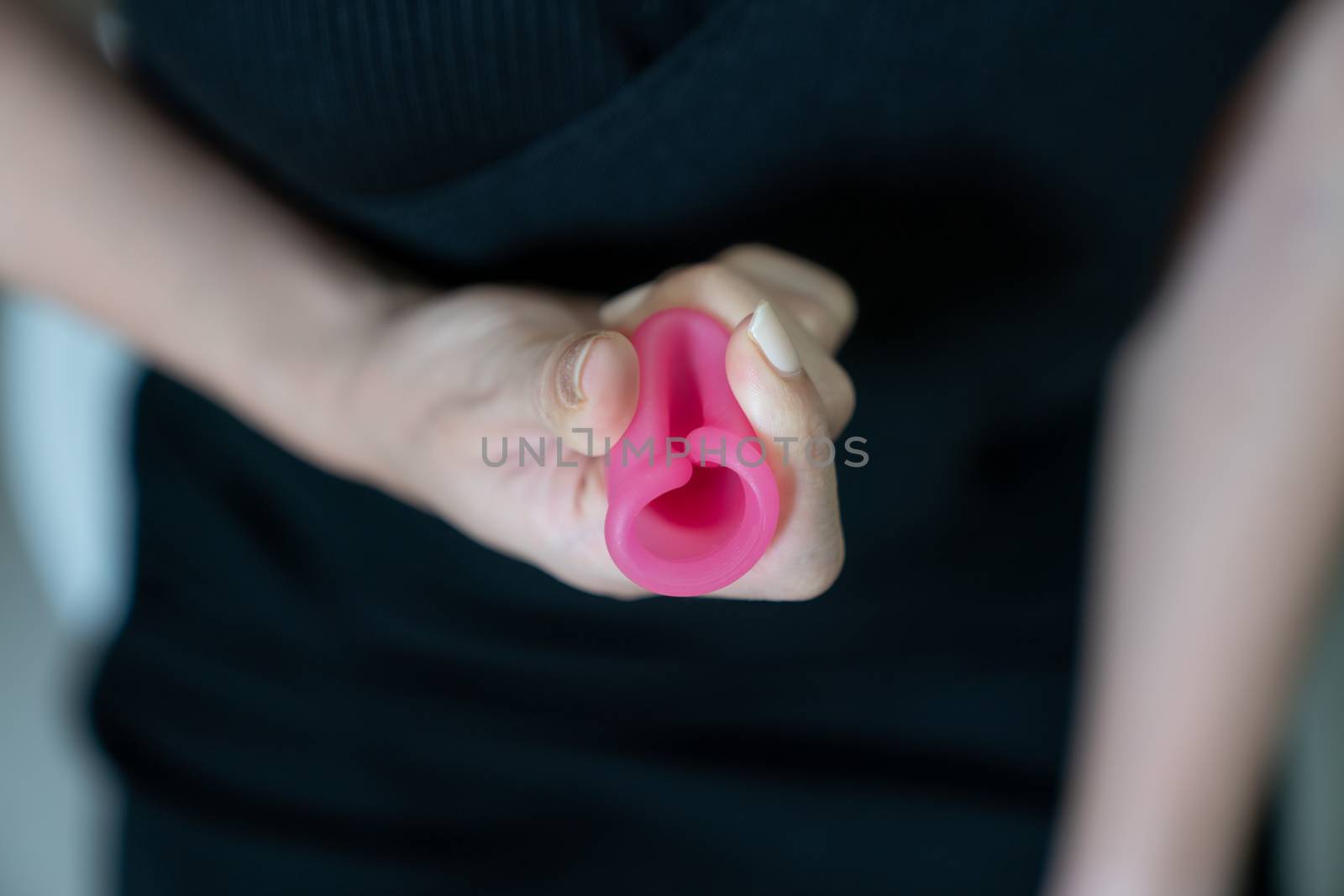 Woman hand holding menstrual cup in toilet. Selective focus. Concept of hygiene.