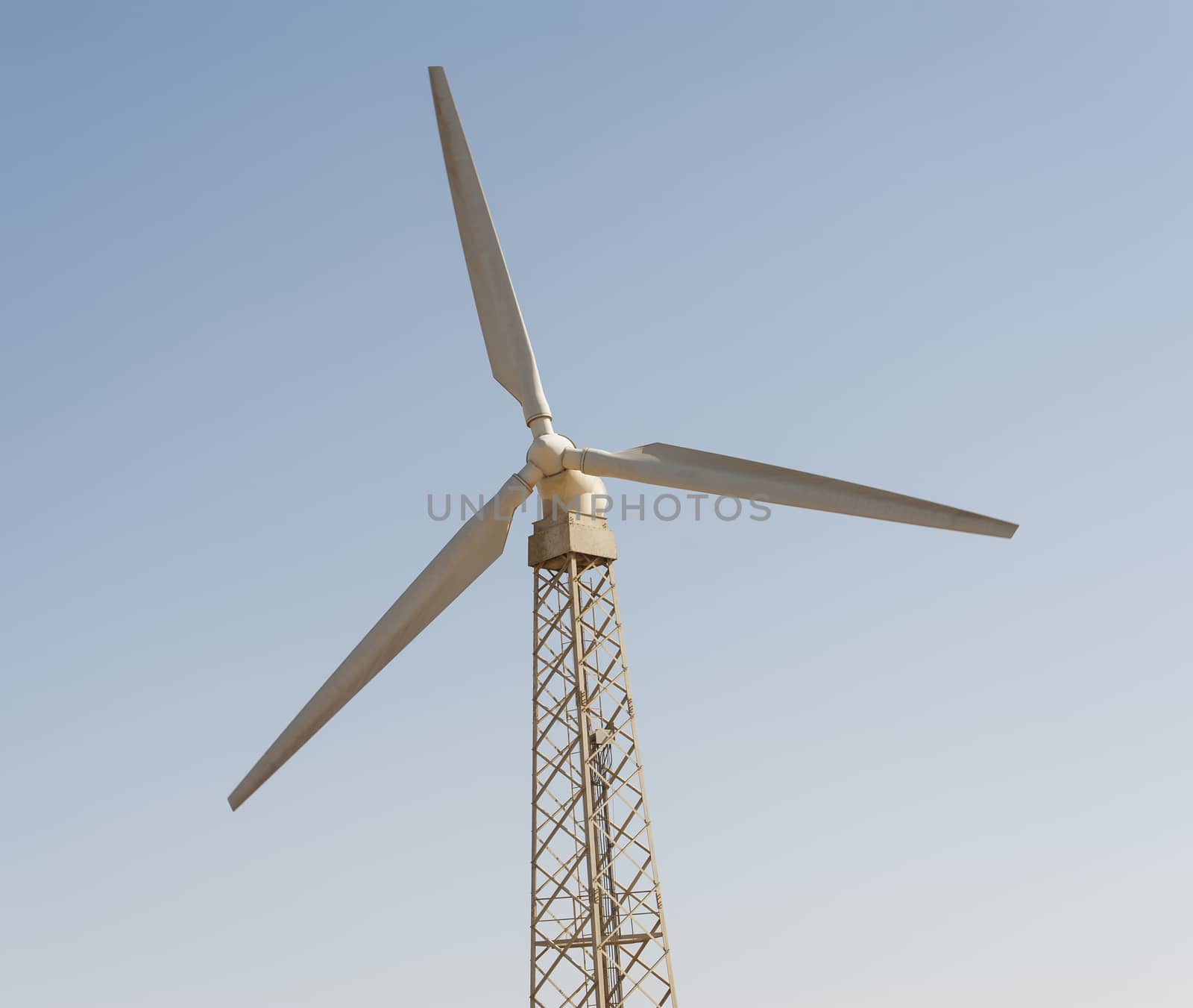 Electric wind turbine generator against a blue sky background