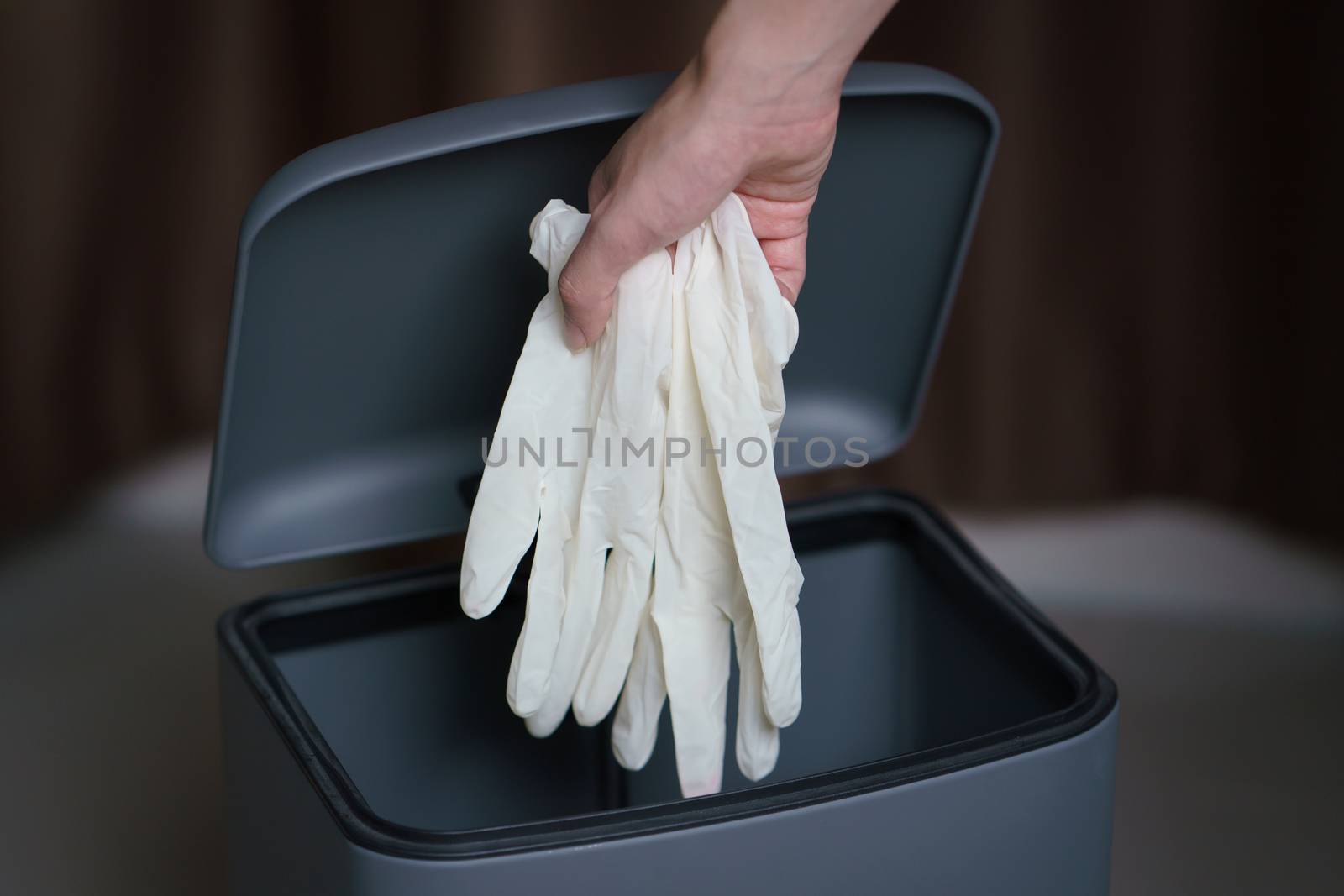 Hand putting used dirty surgical glove to a garbage bin. Mask protect dust and corona virus in trash.