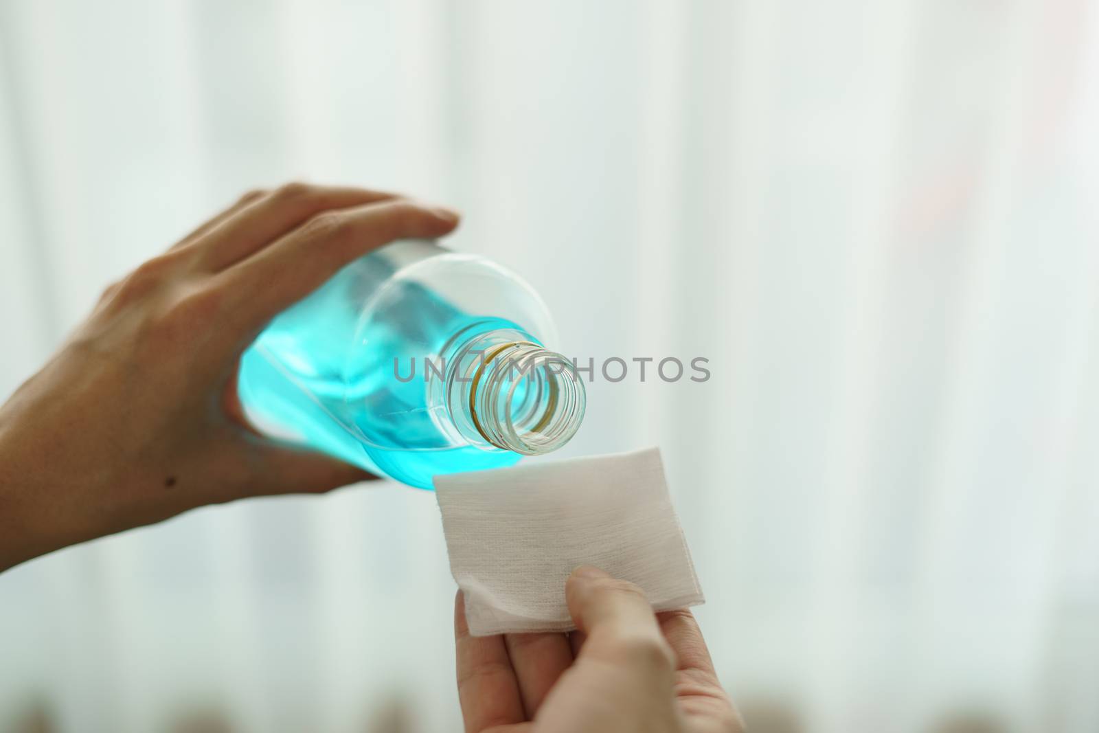 Pouring ethyl alcohol from bottle into a cotton piece for corona virus or Covid-19 protection.