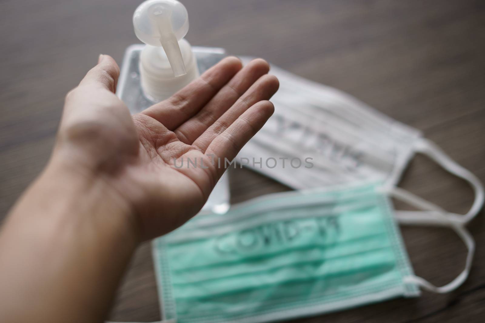 man washing hands with alcohol gel or sanitizer gel. corona virus or Covie-19 protection. with surgical mask with corona virus (covid-19) text written.