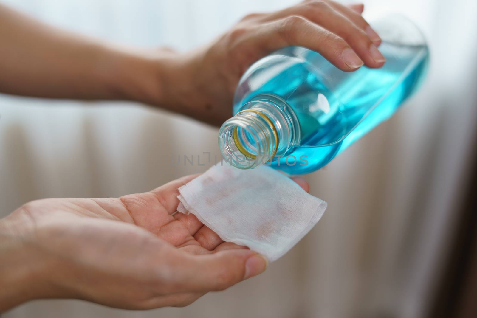 Pouring ethyl alcohol from bottle into a cotton piece for corona virus or Covid-19 protection.