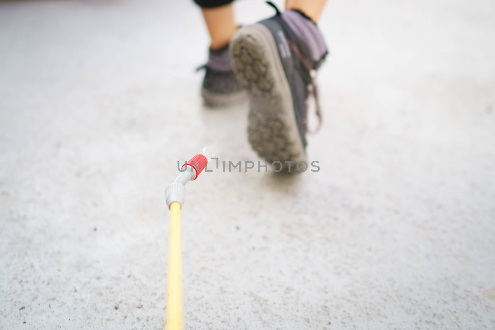 Worker with spray the cleaning sanitize chemical to disinfect COVID-19 virus pathogen on shoes.