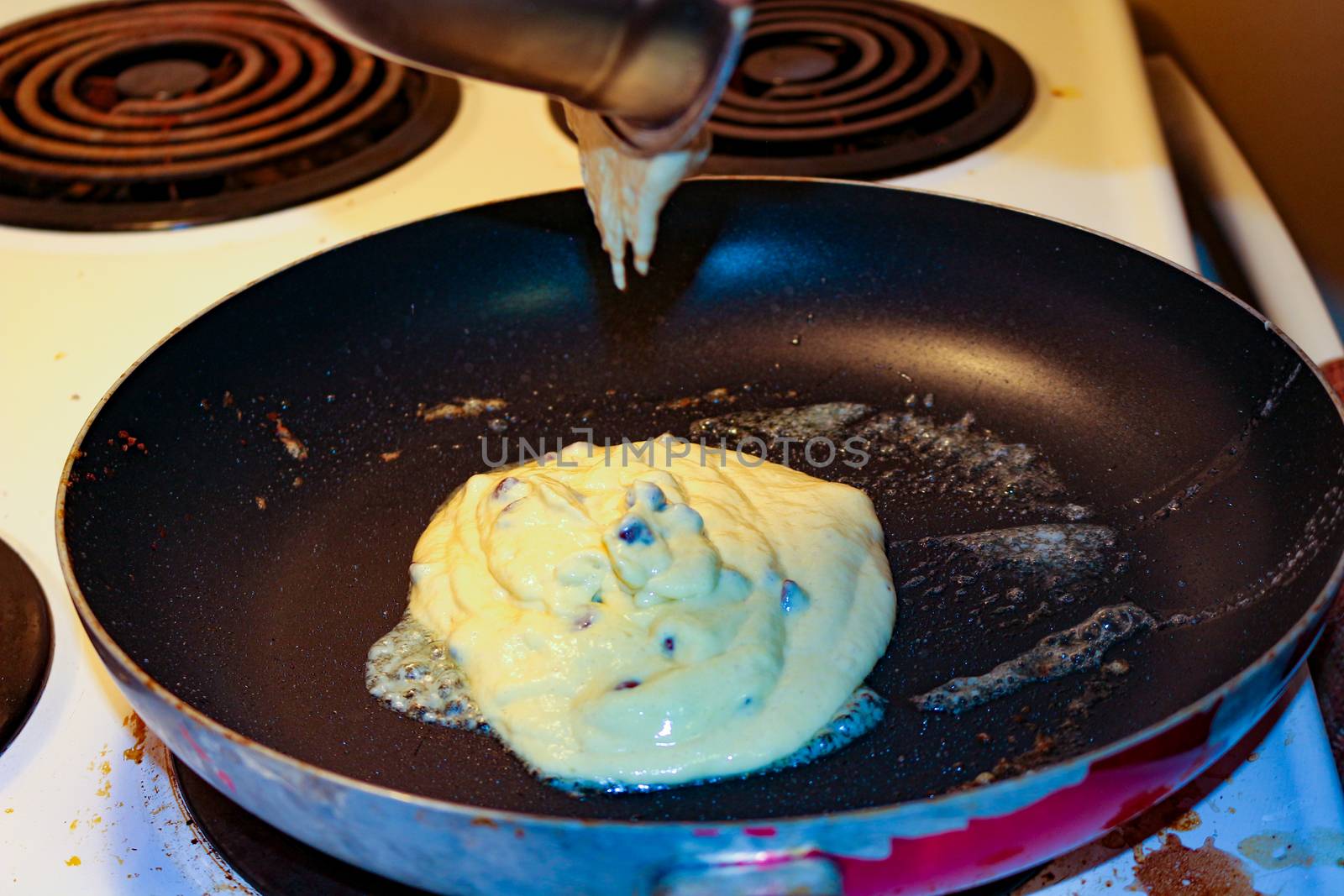 Chocolate chip pancake cooking on stove top frying pan. by mynewturtle1