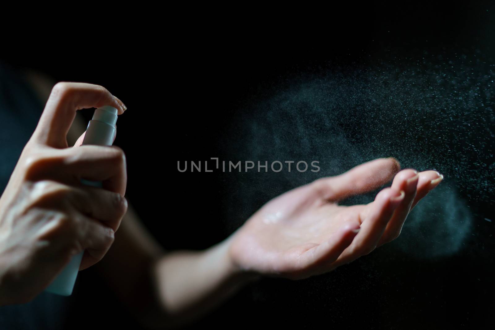 Woman hand using sanitizer spray, alcohol spraying disinfectant to stop spreading coronavirus or COVID-19.