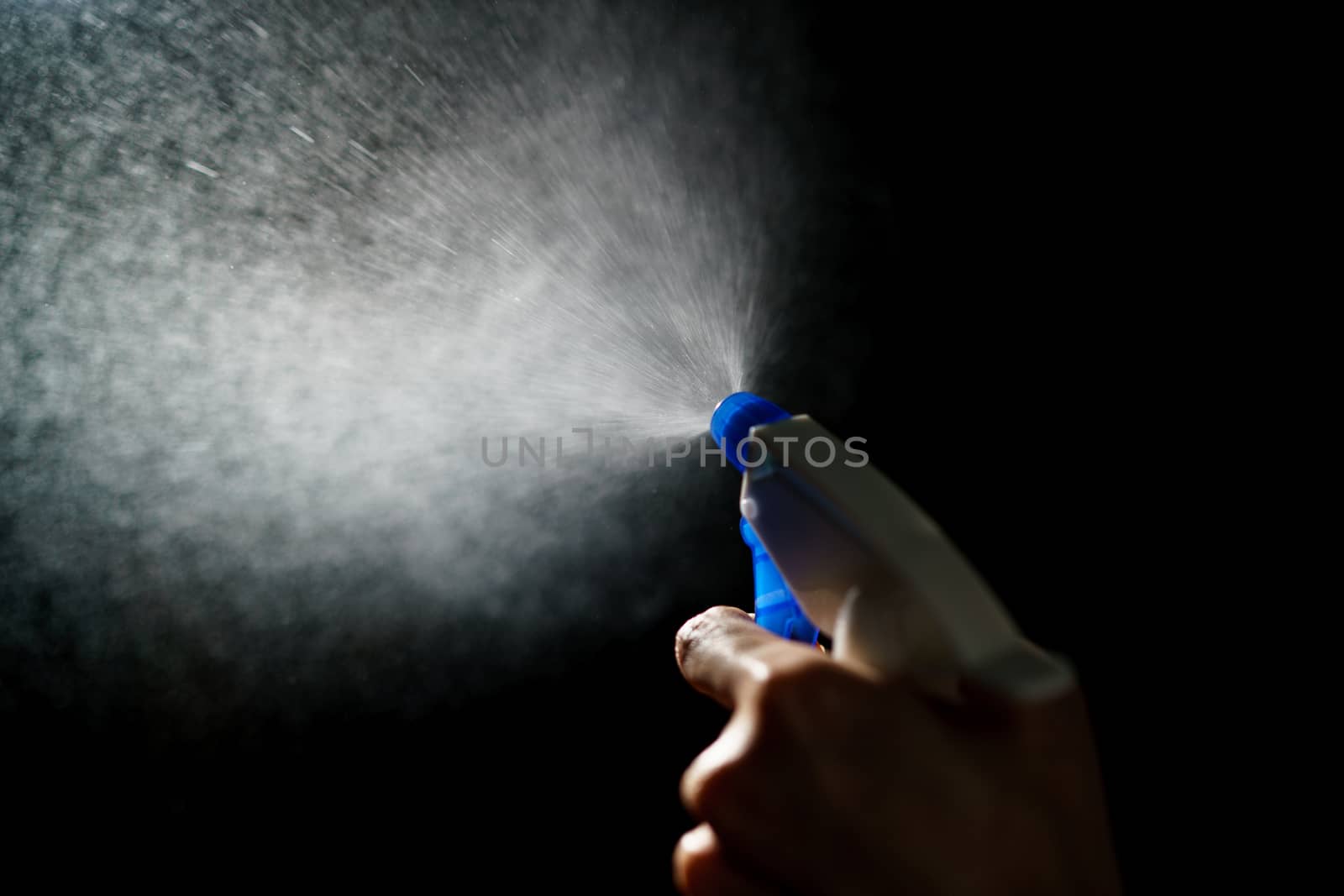 Woman's hands with blue foggy spraying disinfectant to stop spreading coronavirus or COVID-19.