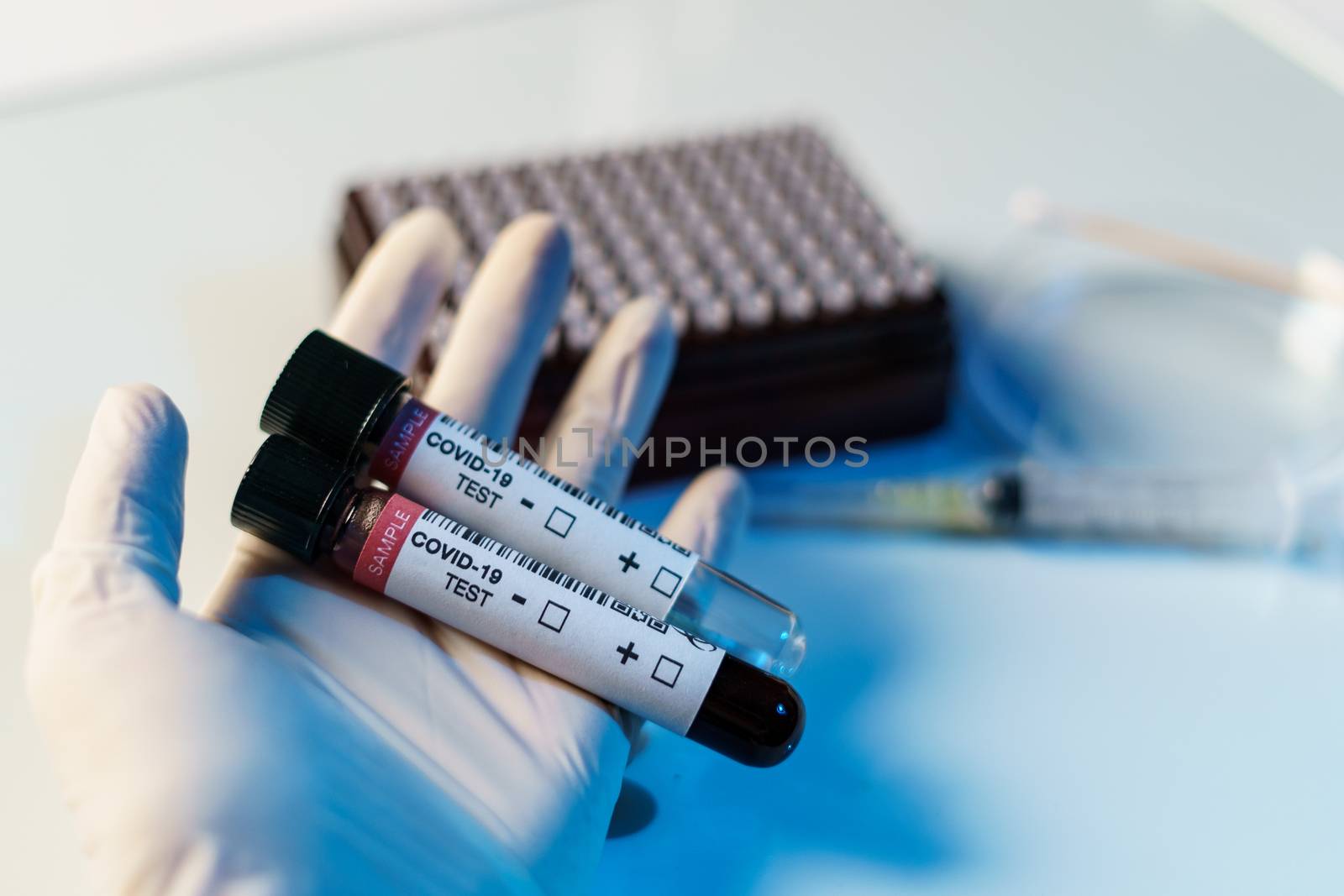 Coronavirus testing process, a hand holds tube of blood test samples and swab collection kit specimen sample testing.