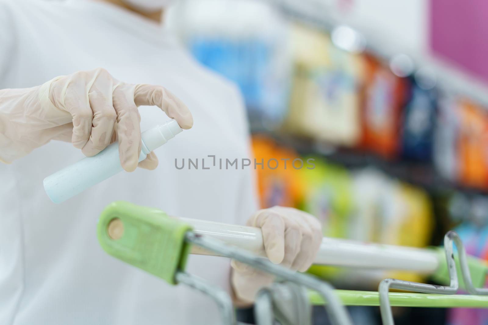 Woman hand disinfecting shopping cart with alcohol spray for corona virus or Covid-19 protection.