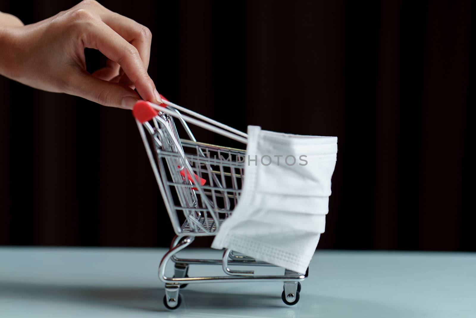 Hands pushing shopping cart with protective face mask corona virus or Covid-19 protection.