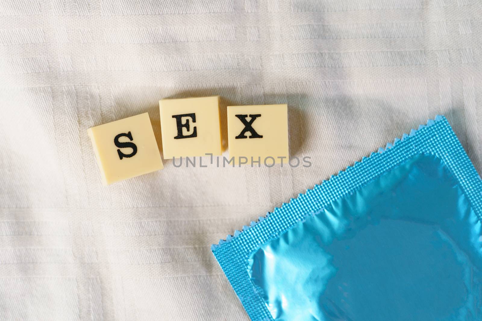 Condom with alphabet showing words SEX on bed . Safe sex concept.