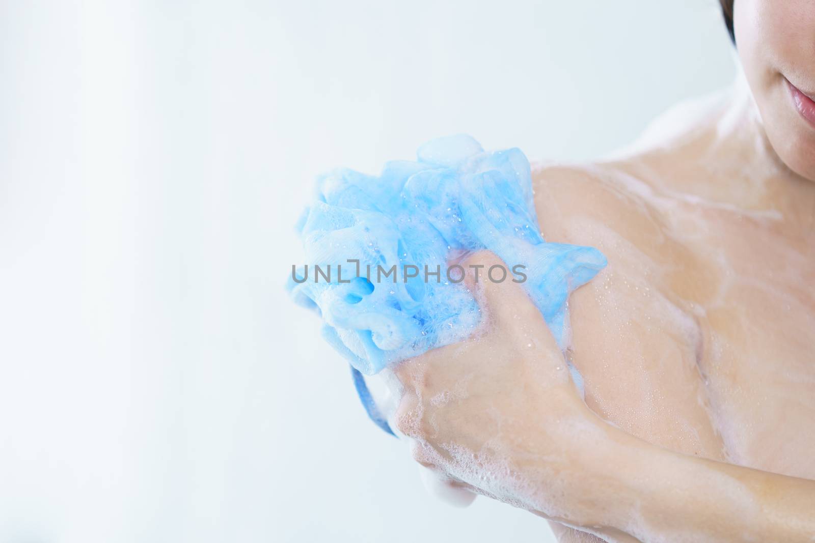 Woman washing her body with bath sponge.