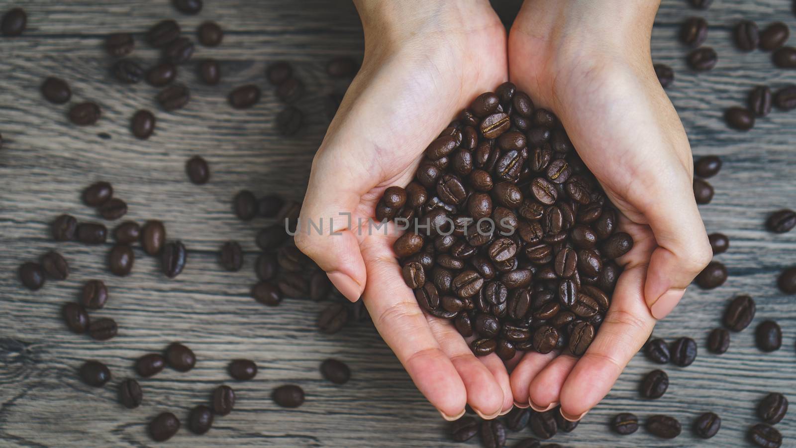 Woman's hands holding roasted coffee beans, closeup by sirawit99