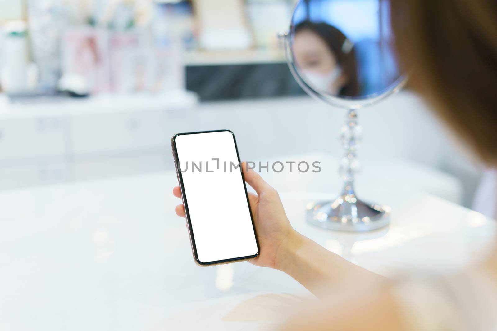 Mockup image of hand holding mobile phone with blank white screen.