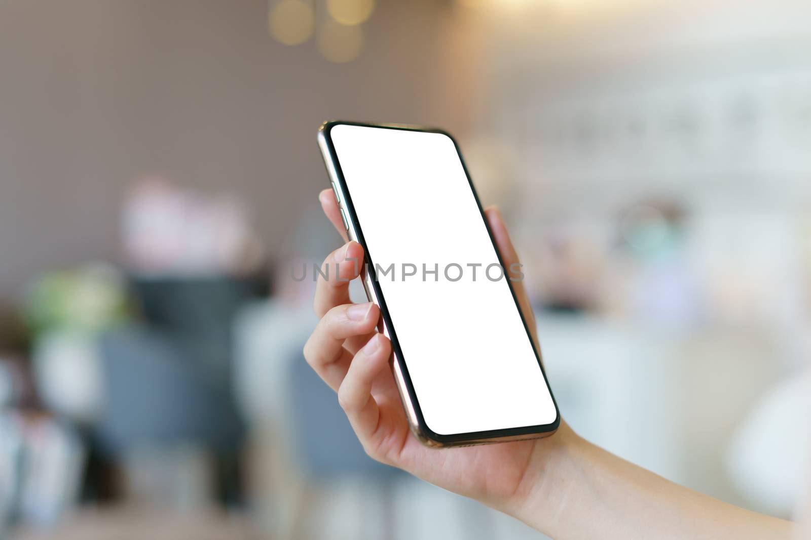 Mockup image of hand holding mobile phone with blank white screen.