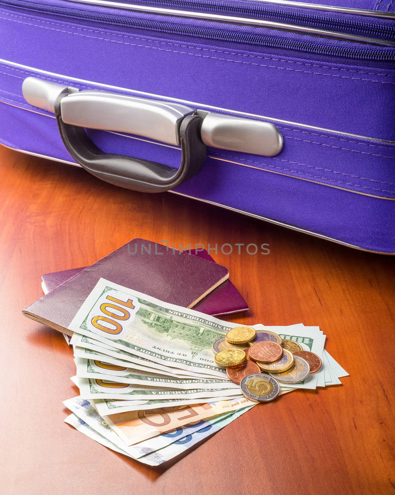 Dollars, Euros and Passports with a violet suitcase, ready for a business or holiday travel abroad.