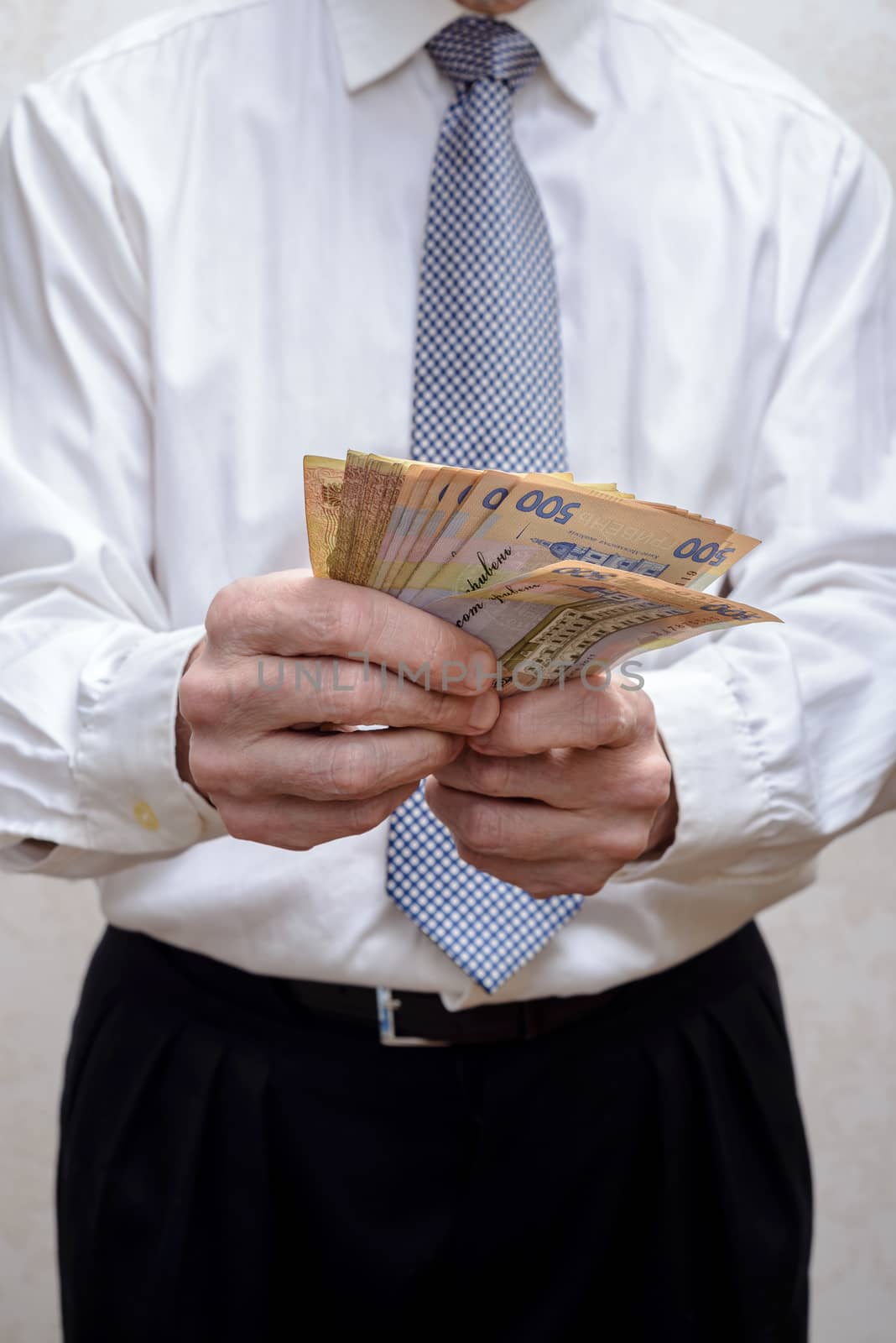 Businessman, or politician, counting a Hryvnia banknotes bribe f by MaxalTamor